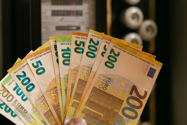 Paying electricity bills in Europe. Electricity cost.Hand holding euro bills on electric meter background. Rising electricity prices. Payment for utility services