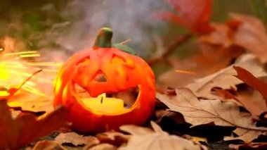 Halloween season. Burning Jack lantern.Pumpkin, brown leaves on stump on sparks and smoke background.Halloween festive background.Festive pumpkin symbol. 4k footage