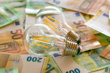  light bulbs on euro bills.Electricity cost.Rising electricity prices in Europe. Crisis of energy production in the EU countries.Increasing the cost of light and heat.Saving electricity concept