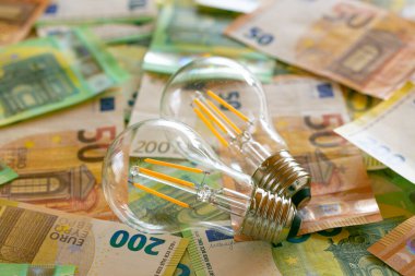 Electricity cost.Two light bulbs on euro bills.Rising electricity prices in Europe.Crisis of energy production in the EU countries.Increasing the cost of light and heat.Saving electricity concept