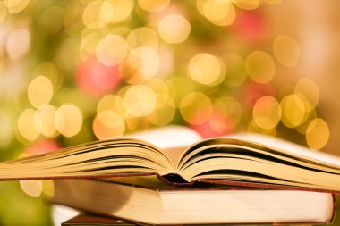  Books on Christmas and winter themes.Stack of books on the table on shining twinkling garlands background.Cozy reading in the winter season.Christmas tales, stories, myths and legends.