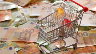Electricity bills.Light bulb in a shopping cart,euro bills on euro banknotes background.Rising electricity prices in Europe.Saving electricity concept