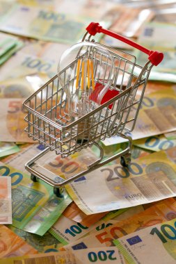 Electricity cost. Rising electricity prices in Europe. Light bulb in a shopping cart,euro bills.Crisis of energy in the EU countries.Saving electricity concept