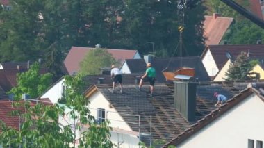 builders on the roof of the house.Roof repair and tile replacement.Workers remove old tiles from the roof. Preparatory building work. Builders on scaffolding on city background.