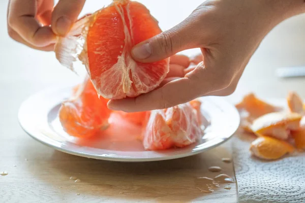 grapefruit.Citrus fruit. hands peeling a grapefruit.Fresh and juicy grapefruit.Splashes and drops of grapefruit juice.Fruit for breakfast.