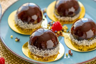  Mavi tabakta ahududu soslu kek ve arka planda bej bir masada çikolata dekoru. Meyveli tatlı. Nefis, havadar bir pasta suflesi..