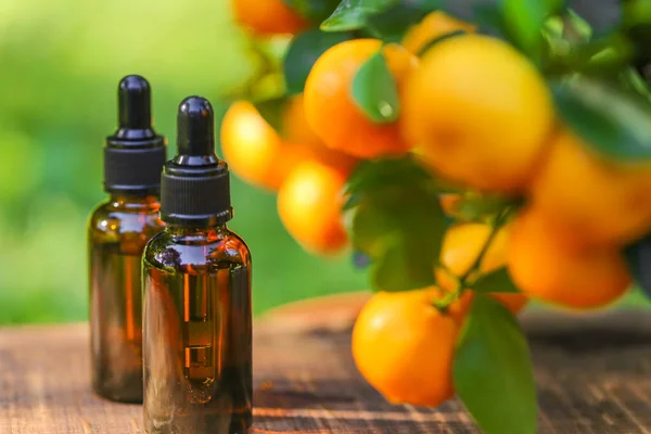 Citrus essential oil.tangerine essential oil.Natural organic oil. brown bottles with oil on a brown wood background and tangerines with green leaves.Organic natural eco cosmetics.