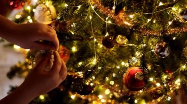 Noel ağacını Noel oyuncaklarıyla süslemek. Çocuklar Noel ağacını parlak toplarla süsler. Elleri parlak çelenklerle dolu bir ladin dalına bir top asar.