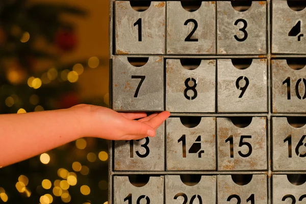 advent calendar.Gifts and surprises for Christmas and New Year.retro advent calendar and childs hand on lights garlands background.hand opens the advent calendar.