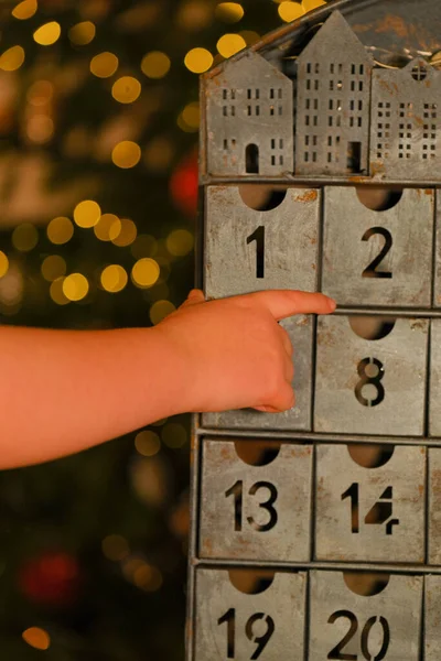 advent calendar in vintage style and childs hand on garlands background.hand opens the advent calendar. traditions and symbols.Gifts and surprises for Christmas and New Year