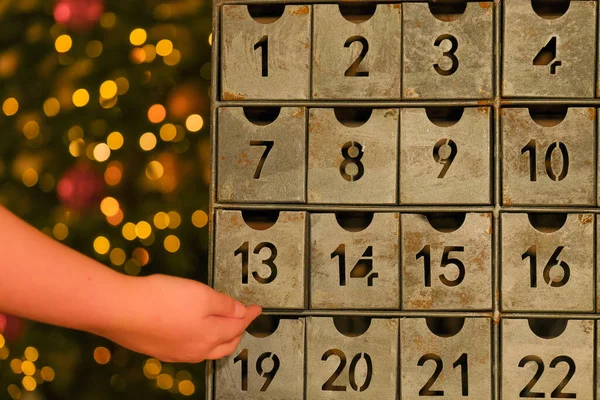 advent calendar.Metallic retro advent calendar in vintage style and childs hand .hand opens the advent calendar. traditions and symbols.Gifts and surprises for Christmas and New Year