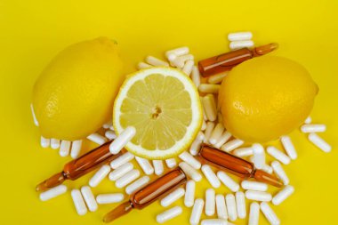 Sarı arka planda C vitamini hapları. Uçan C vitamini hapları ve limon kesimi. Doğal Meyve Vitamini C.dokunulmazlığı. Sağlık ve İlaç. 