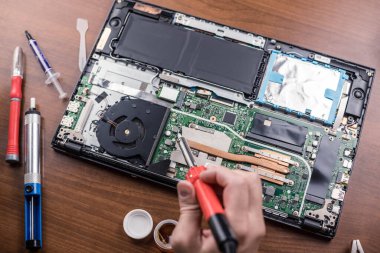 Elde lehim, parçalanmış dizüstü bilgisayar. Üst Manzara. Tamirci. Aletleri olan bir işçi. Bilgisayar teçhizatı. Dijital bir cihaz. Laptop masanın üstünde. Elektronik Cihazlar Konsepti..