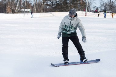 Bir snowboardcu karla kaplı bir yamaçtan aşağı yuvarlanıyor. Kışın açık hava aktiviteleri. Boşluğu Kopyala
