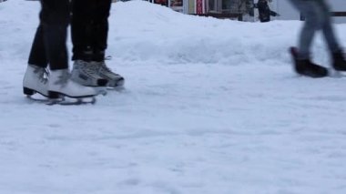 İnsanlar kışın açık havada buz pateni pistinde paten kayarlar. Patenli bacakları yakın plan, yüzü yok. Kış sporu - buz pateni