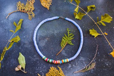 Renkli kolye ve bilezik karışımı, boncuklar ve taş kolye, mavi arka planda mücevherler.