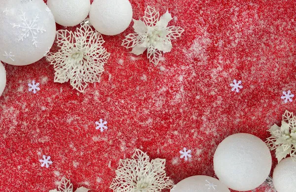 クリスマスの装飾 白い玉 白い透かし彫りの花のポインセチア 赤いキラキラした背景の雪の上の雪片 トップビュー フラットレイアウト — ストック写真
