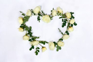 Beyaz güllerin çerçevesi hafif arkaplan üzerinde kalp şeklinde ve yazı için yeri var. Üst manzara, düz yatış. Sevgililer Günü dekorasyonu