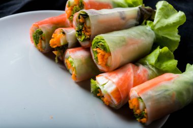 Beyaz arka plandaki Asya sokak yemeklerine izole edilmiş tabakta erişte tüpünde taze sebze salatası rulosu.