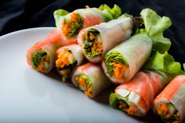 Beyaz arka plandaki Asya sokak yemeklerine izole edilmiş tabakta erişte tüpünde taze sebze salatası rulosu.