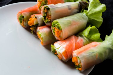 Beyaz arka plandaki Asya sokak yemeklerine izole edilmiş tabakta erişte tüpünde taze sebze salatası rulosu.