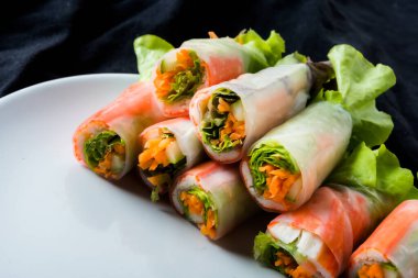 Beyaz arka plandaki Asya sokak yemeklerine izole edilmiş tabakta erişte tüpünde taze sebze salatası rulosu.