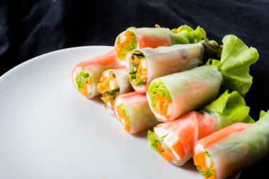 Beyaz arka plandaki Asya sokak yemeklerine izole edilmiş tabakta erişte tüpünde taze sebze salatası rulosu.