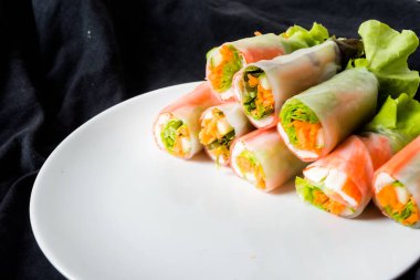 Beyaz arka plandaki Asya sokak yemeklerine izole edilmiş tabakta erişte tüpünde taze sebze salatası rulosu.