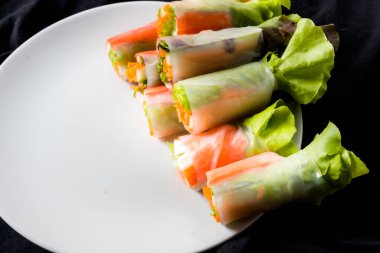 Beyaz arka plandaki Asya sokak yemeklerine izole edilmiş tabakta erişte tüpünde taze sebze salatası rulosu.