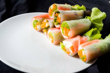 Beyaz arka plandaki Asya sokak yemeklerine izole edilmiş tabakta erişte tüpünde taze sebze salatası rulosu.