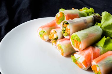 Beyaz arka plandaki Asya sokak yemeklerine izole edilmiş tabakta erişte tüpünde taze sebze salatası rulosu.