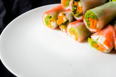 Beyaz arka plandaki Asya sokak yemeklerine izole edilmiş tabakta erişte tüpünde taze sebze salatası rulosu.