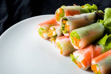 Beyaz arka plandaki Asya sokak yemeklerine izole edilmiş tabakta erişte tüpünde taze sebze salatası rulosu.