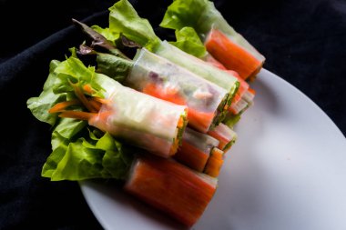 Beyaz arka plandaki Asya sokak yemeklerine izole edilmiş tabakta erişte tüpünde taze sebze salatası rulosu.