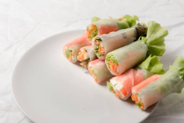 Beyaz arka plandaki Asya sokak yemeklerine izole edilmiş tabakta erişte tüpünde taze sebze salatası rulosu.