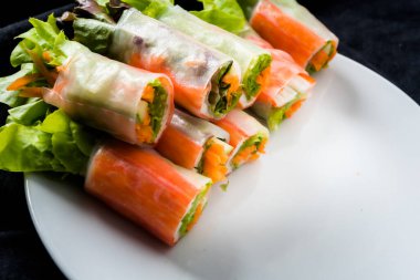 Beyaz arka plandaki Asya sokak yemeklerine izole edilmiş tabakta erişte tüpünde taze sebze salatası rulosu.