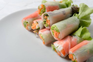 Beyaz arka plandaki Asya sokak yemeklerine izole edilmiş tabakta erişte tüpünde taze sebze salatası rulosu.