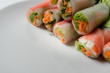 Beyaz arka plandaki Asya sokak yemeklerine izole edilmiş tabakta erişte tüpünde taze sebze salatası rulosu.