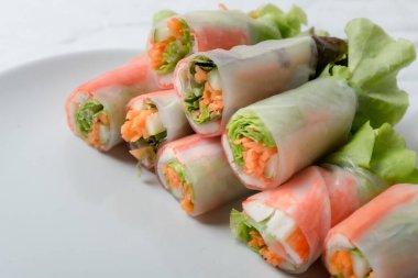 Beyaz arka plandaki Asya sokak yemeklerine izole edilmiş tabakta erişte tüpünde taze sebze salatası rulosu.