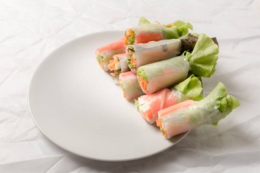 Beyaz arka plandaki Asya sokak yemeklerine izole edilmiş tabakta erişte tüpünde taze sebze salatası rulosu.