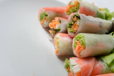 Beyaz arka plandaki Asya sokak yemeklerine izole edilmiş tabakta erişte tüpünde taze sebze salatası rulosu.