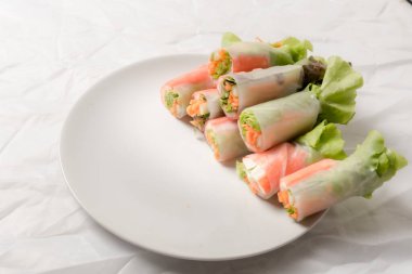 Beyaz arka plandaki Asya sokak yemeklerine izole edilmiş tabakta erişte tüpünde taze sebze salatası rulosu.