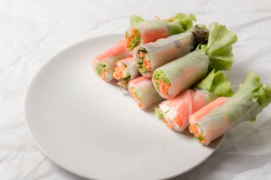 Beyaz arka plandaki Asya sokak yemeklerine izole edilmiş tabakta erişte tüpünde taze sebze salatası rulosu.