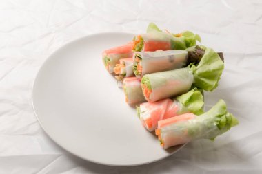 Beyaz arka plandaki Asya sokak yemeklerine izole edilmiş tabakta erişte tüpünde taze sebze salatası rulosu.