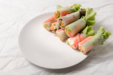 Beyaz arka plandaki Asya sokak yemeklerine izole edilmiş tabakta erişte tüpünde taze sebze salatası rulosu.