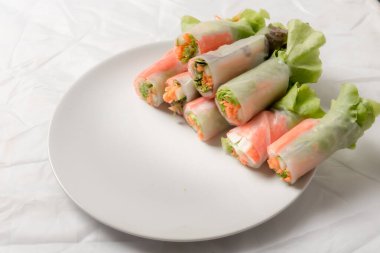 Beyaz arka plandaki Asya sokak yemeklerine izole edilmiş tabakta erişte tüpünde taze sebze salatası rulosu.