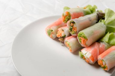 Beyaz arka plandaki Asya sokak yemeklerine izole edilmiş tabakta erişte tüpünde taze sebze salatası rulosu.
