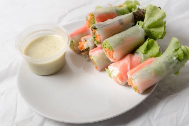 Beyaz arka plandaki Asya sokak yemeklerine izole edilmiş tabakta erişte tüpünde taze sebze salatası rulosu.