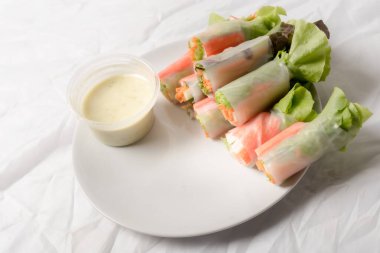 Beyaz arka plandaki Asya sokak yemeklerine izole edilmiş tabakta erişte tüpünde taze sebze salatası rulosu.