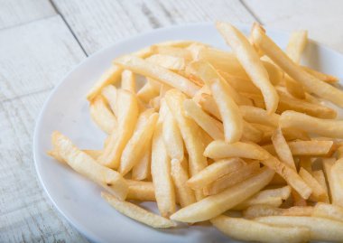 Ahşap tabakta beyaz bir tabakta patates kızartması, barbekü sosu, domates sosu.